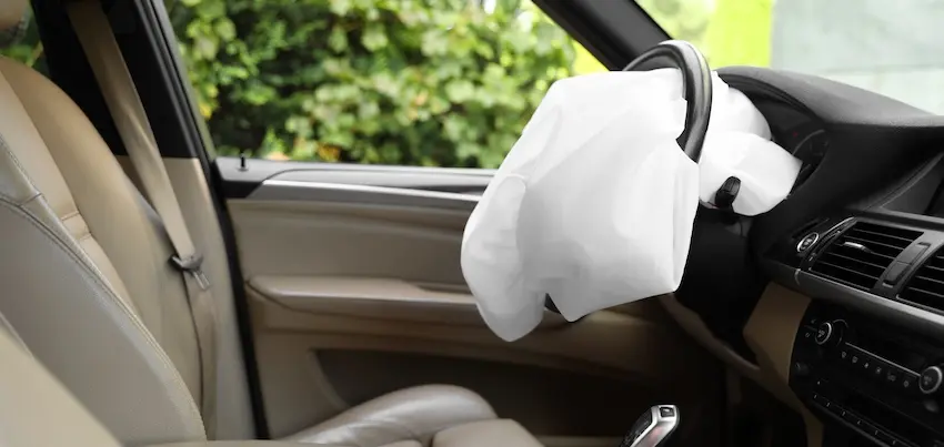 A deployed white airbag is hanging from the steering wheel inside a vehicle after airbag deployment following a collision impact in Atlanta.