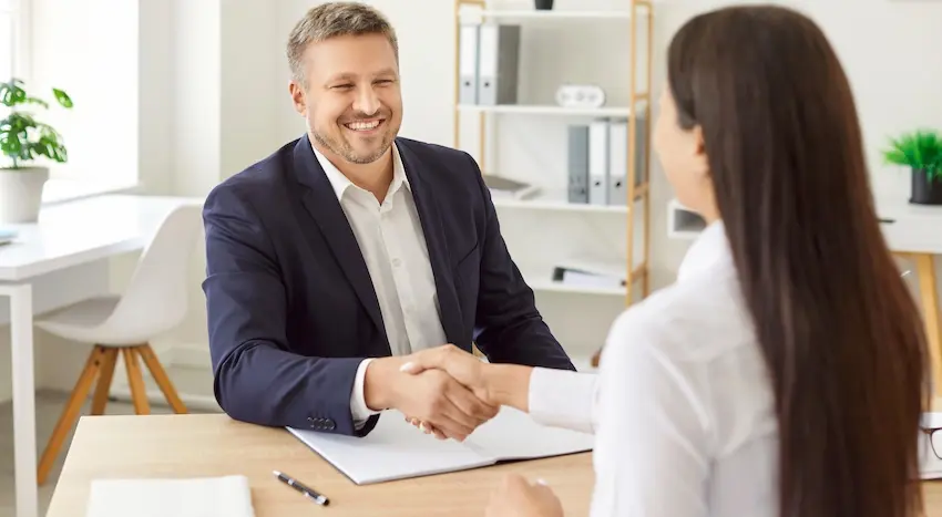 A car accident lawyer is shaking hands with a client during a personal injury case consultation meeting.