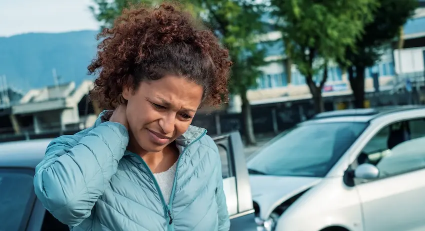 A woman is holding her neck in pain after a car accident requiring health insurance for injury treatment and medical care in Atlanta.
