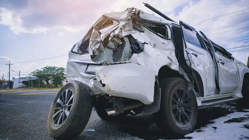 A severely damaged white SUV with a crushed front end and deployed airbag was on the roadside after a serious car accident in Atlanta.