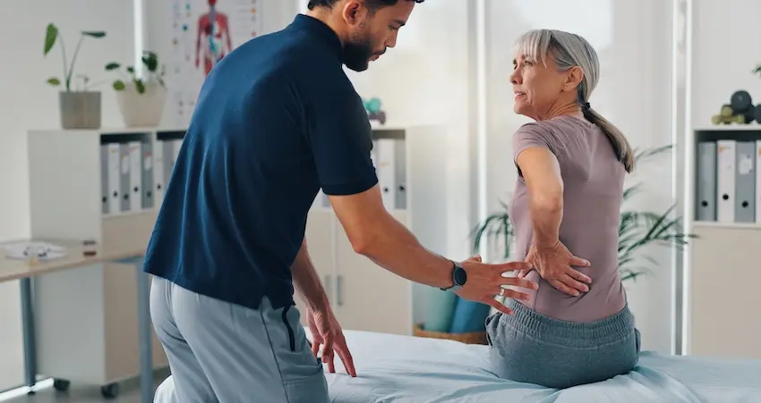A physical therapist is examining a patient with back pain problems and is performing a spinal assessment and diagnosis in the Metro Atlanta area.