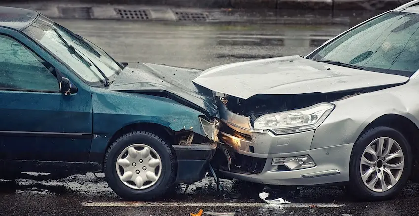 A teal car and a silver car with crumpled hoods locked together after a head-on collision on a rain-soaked road showing the type of serious crash where police never showed up to document the damage and exchange of information in Metro Atlanta.