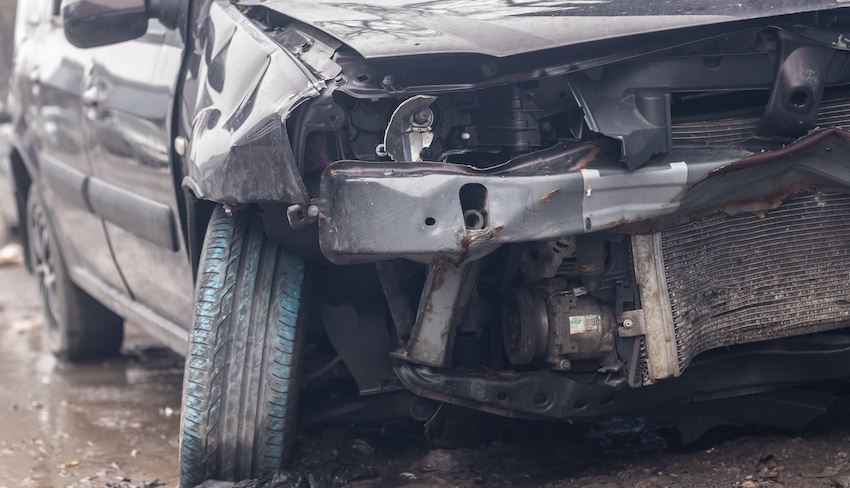 A severely damaged vehicle front end with a crushed bumper and exposed engine from a serious car accident collision in Atlanta.