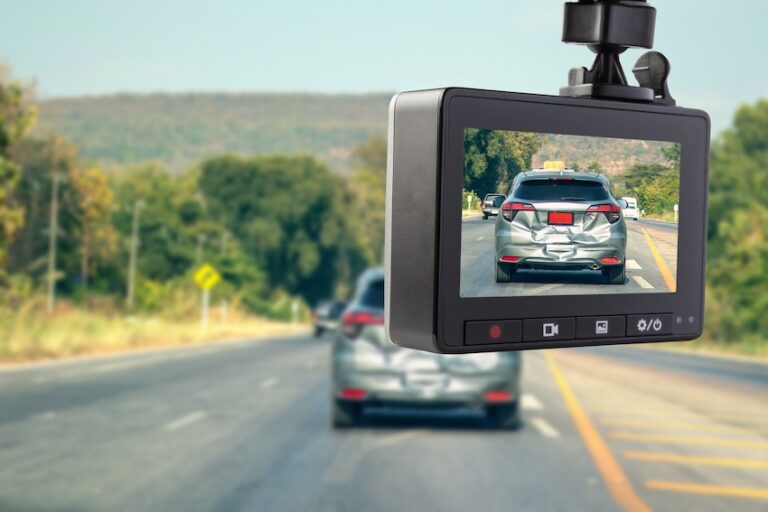 A dashboard camera mounted inside a vehicle displays a clear close-up recording of a silver sedan with rear-end damage driving ahead on a tree-lined highway demonstrating exactly how dashcam video captures critical evidence of a collision that can be used to prove fault in an accident claim in Metro Atlanta.