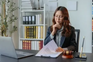 Traumatic brain injury lawyer sitting at a desk, reviewing a case file for a TBI victim. Experienced attorney analyzing medical records and legal documents to build a strong case for maximum compensation.