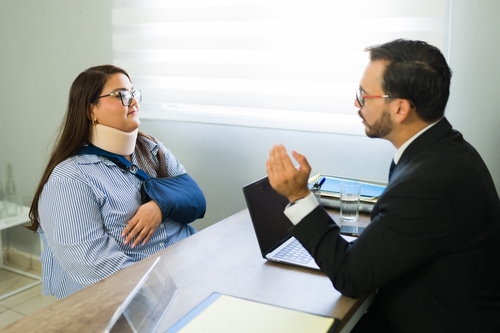 A personal injury lawyer speaking with a woman in an arm brace about her claim.